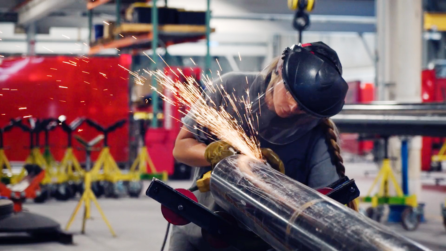 Employee welding object in factory setting.